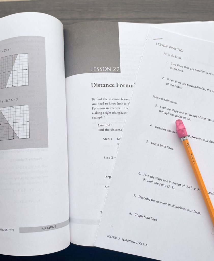 Math-U-See math book opened with a worksheet laying on it and a pencil.