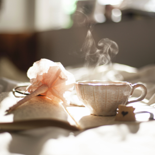 tea cup with steam rising and a pair flower on a book