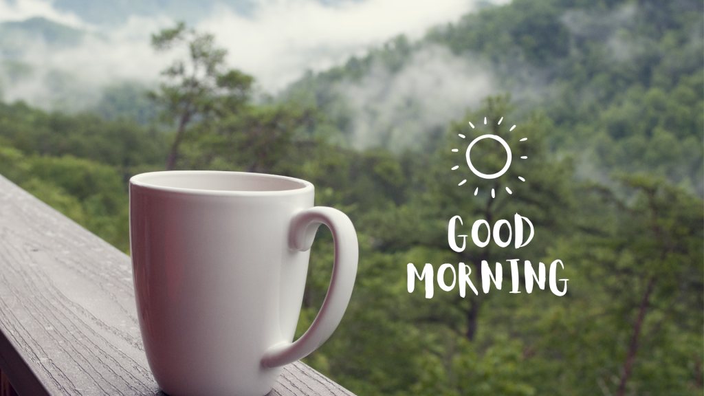Cup of coffee on rail looking out over trees and clouds