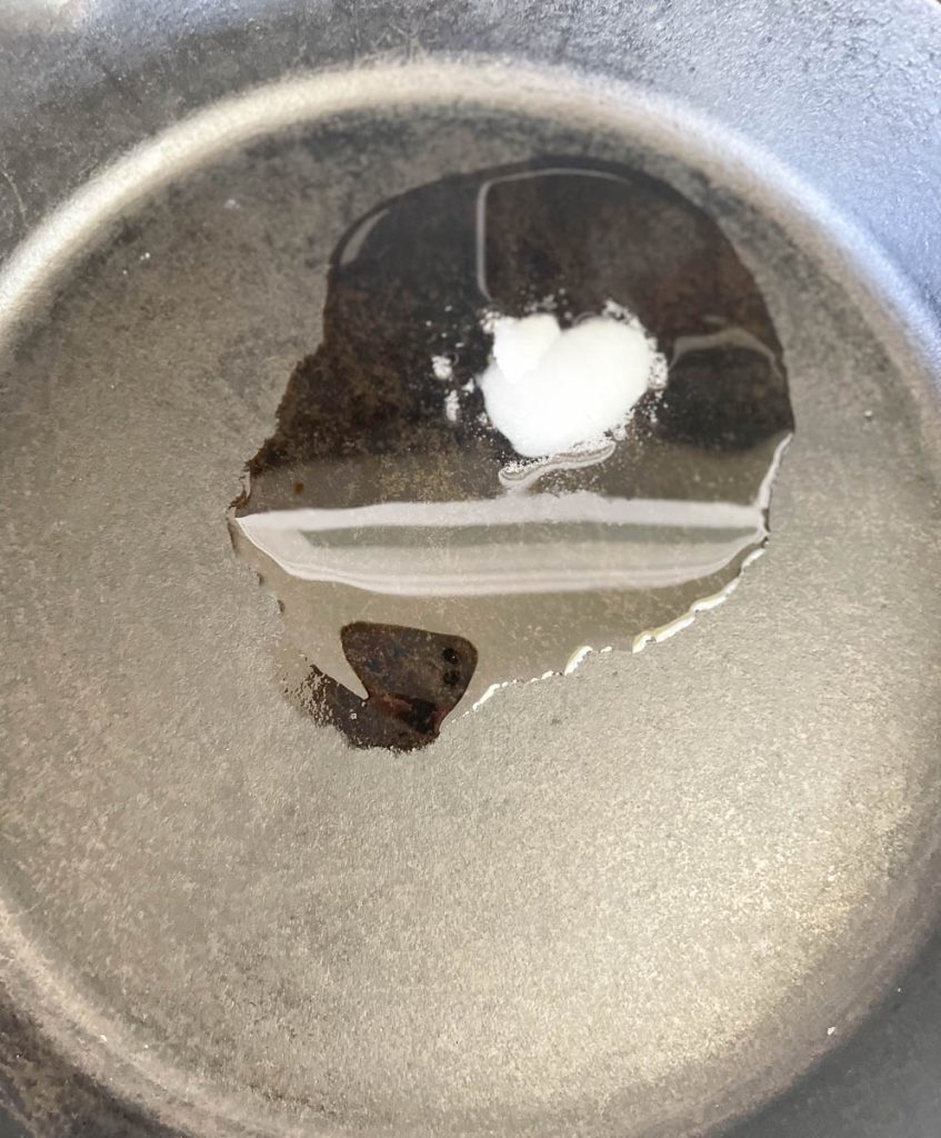 Cast iron skillet with coconut oil melting in it