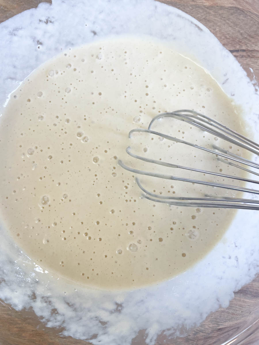 A glass bowl with a bubbly sourdough mixture and a mix